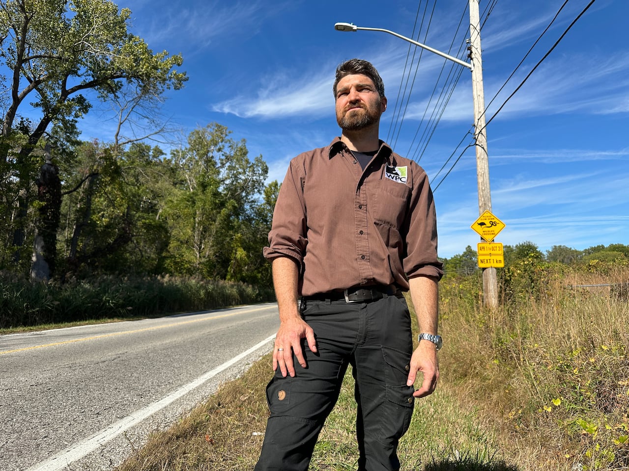 A man standing next to a roadway.