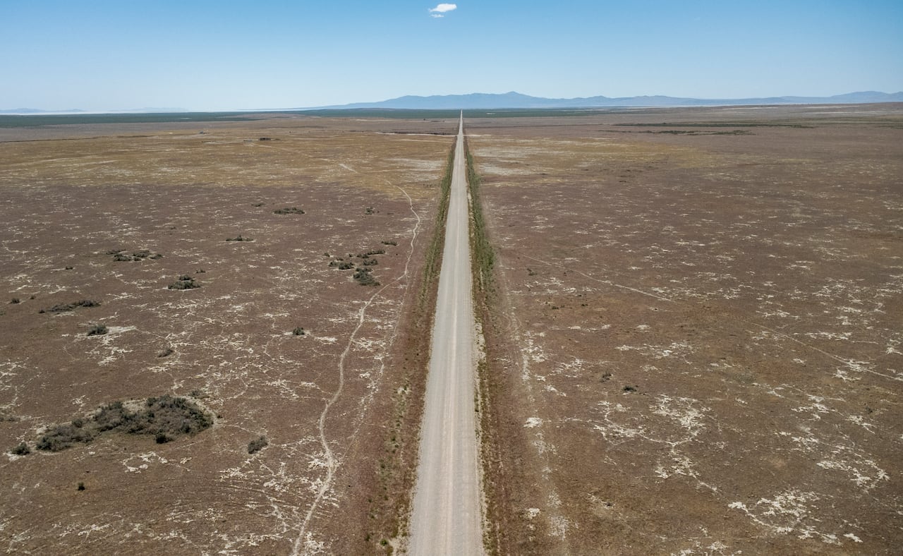An aerial view shows a desert with a road in the middle.