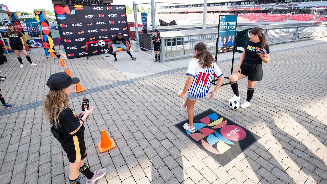 Child kicks ball at CBC host during a community activation.