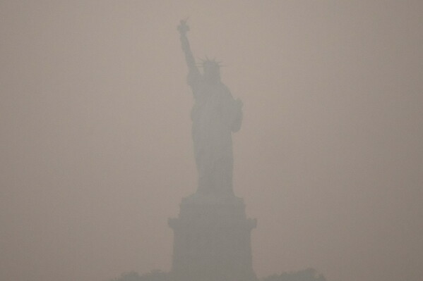 The Statue of Liberty stands during sunset as smoke from wildfires blankets the sky, Thursday, July 16, 2026, in the Brooklyn borough of New York. (AP Photo/Yuki Iwamura)