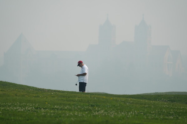 A golfer checks his score card at Willow Hills Golf course during poor air quality due to dense smoke from Canadian wildfires in Northbrook, Ill., Thursday, July 16, 2026. (AP Photo/Nam Y. Huh)