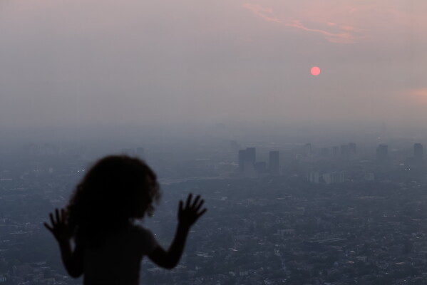 A child looks out from the observation deck of the CN Tower as smoke from wildfires in Northwestern Ontario blankets the city of Toronto, Thursday, July 16, 2026. (Cole Burston/The Canadian Press via AP)