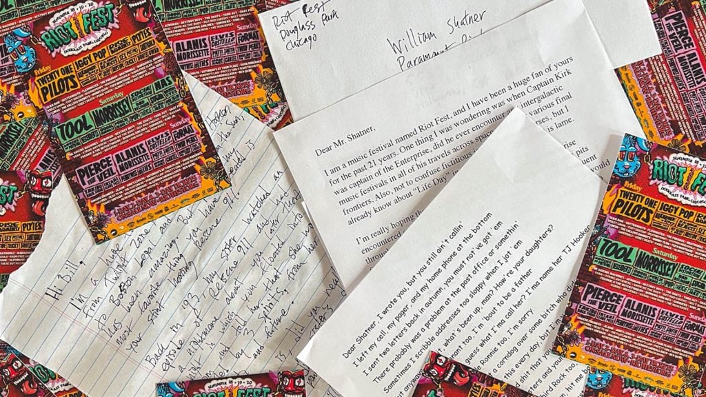 A table full of colourful music festival posters with 3 letters and an envelope address to William Shatner on top.