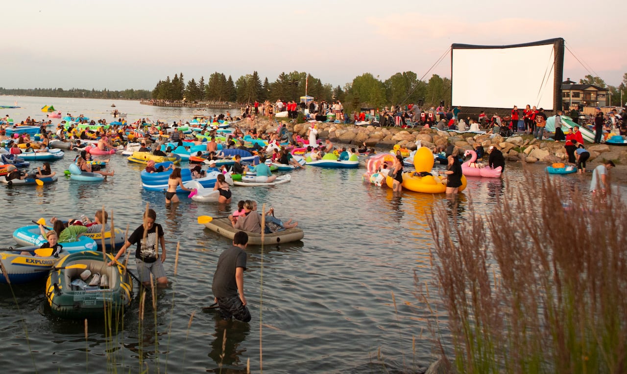 People on floats in the water turning towards a big screen.