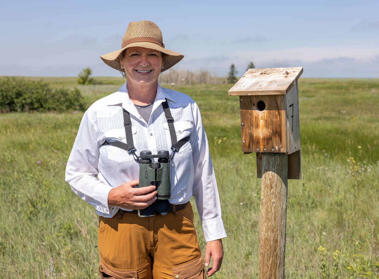 A woman stands next to a nest box.