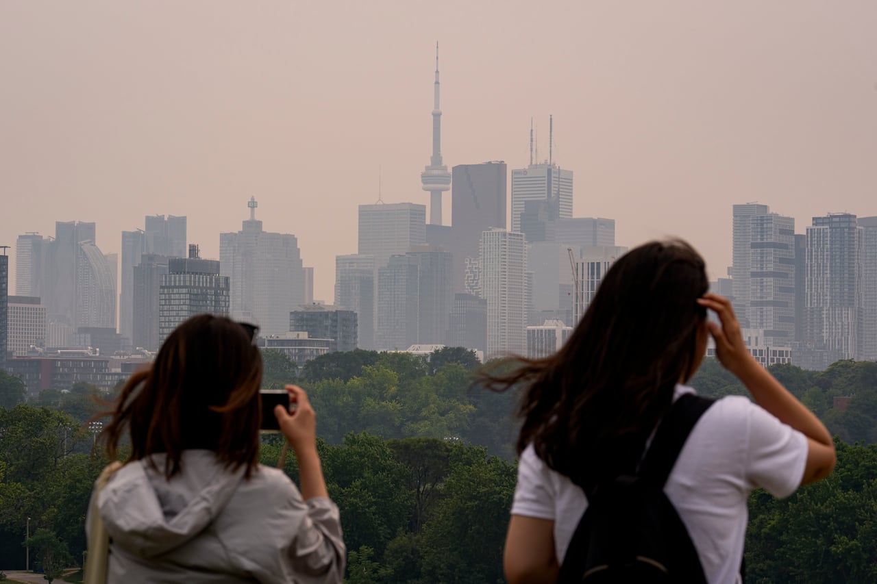 People take photos look out at hazy Toronto skyline.