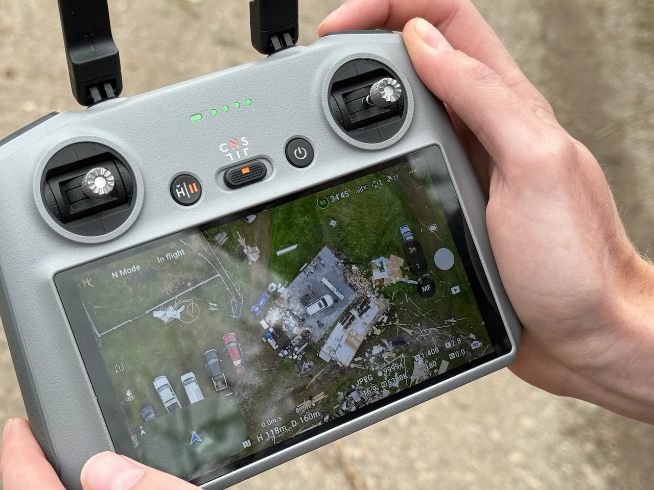 A viewfinder shows drone footage of a home damaged by a tornado.