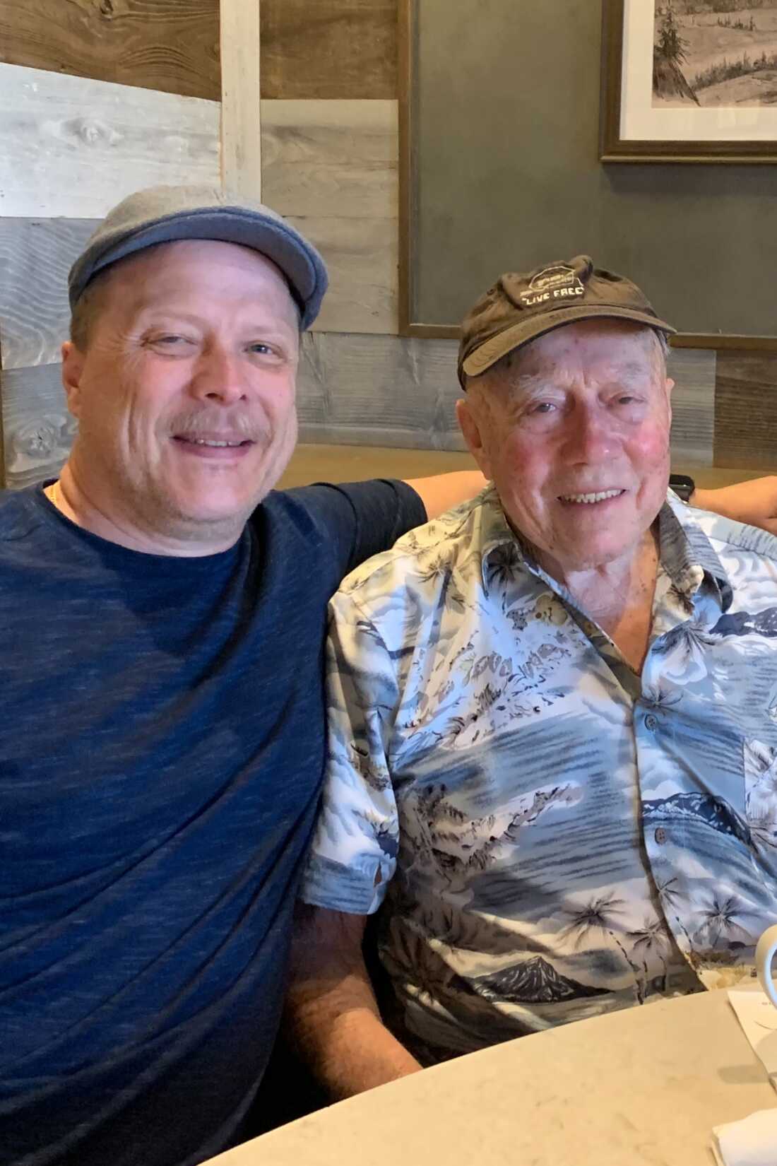 Two smiling men are shown; the younger man has his arm around his father's shoulders.