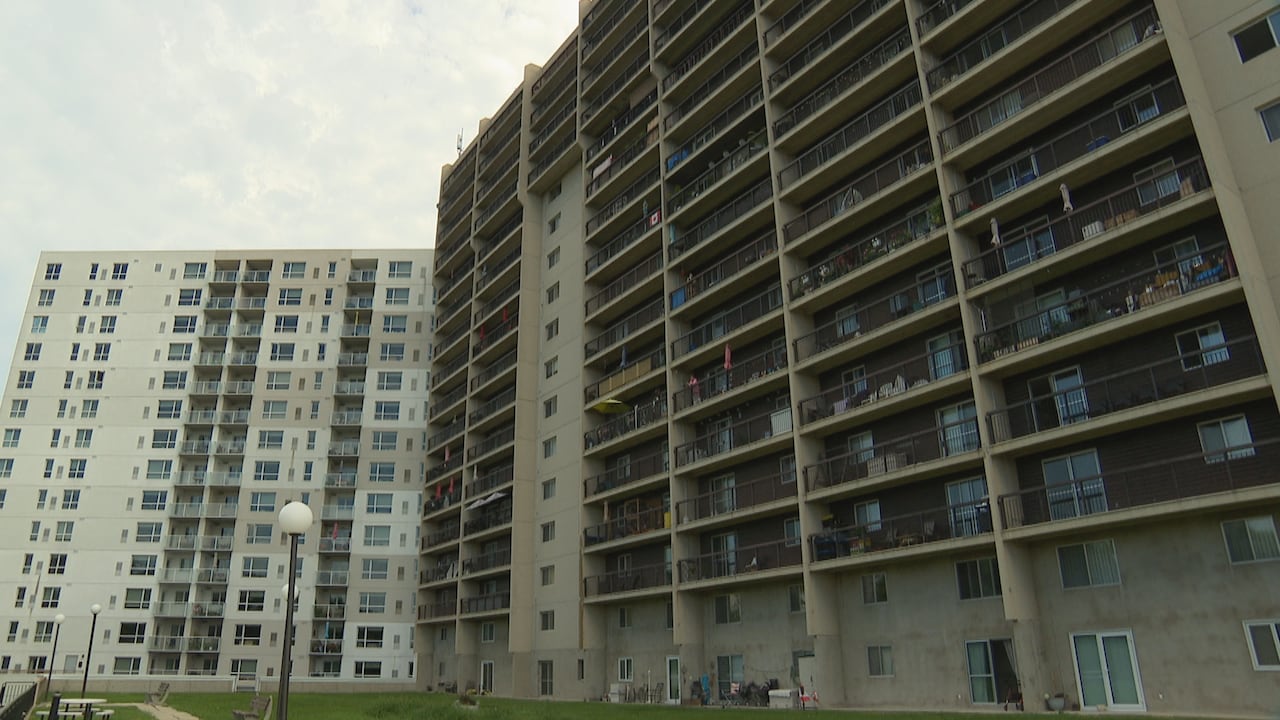 Two tall apartment buildings are seen from the ground up.