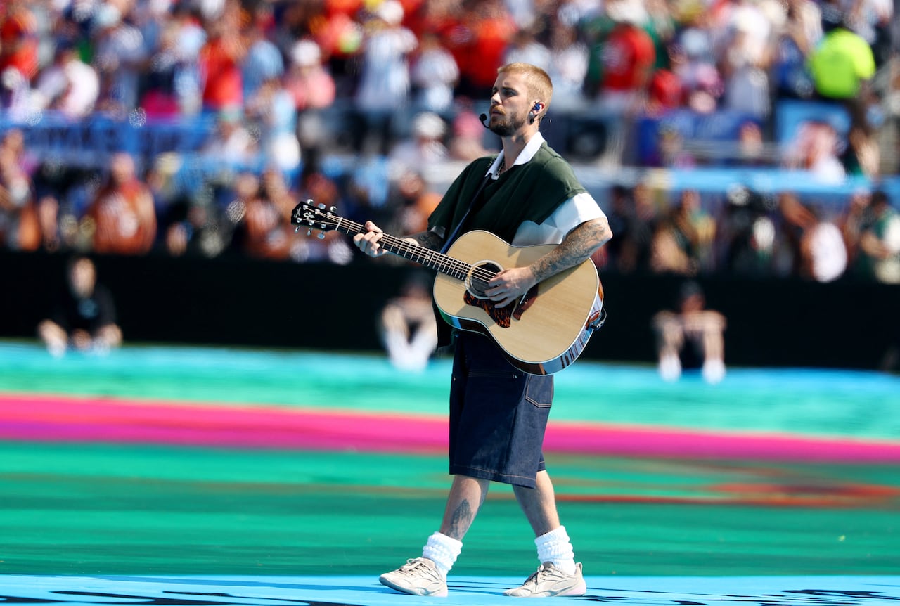 A man sings and plays acoustic guitar while walking in a stadium