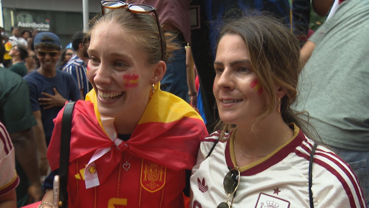 Two women stand side-by-side in Spanish soccer jerseys, smiling.