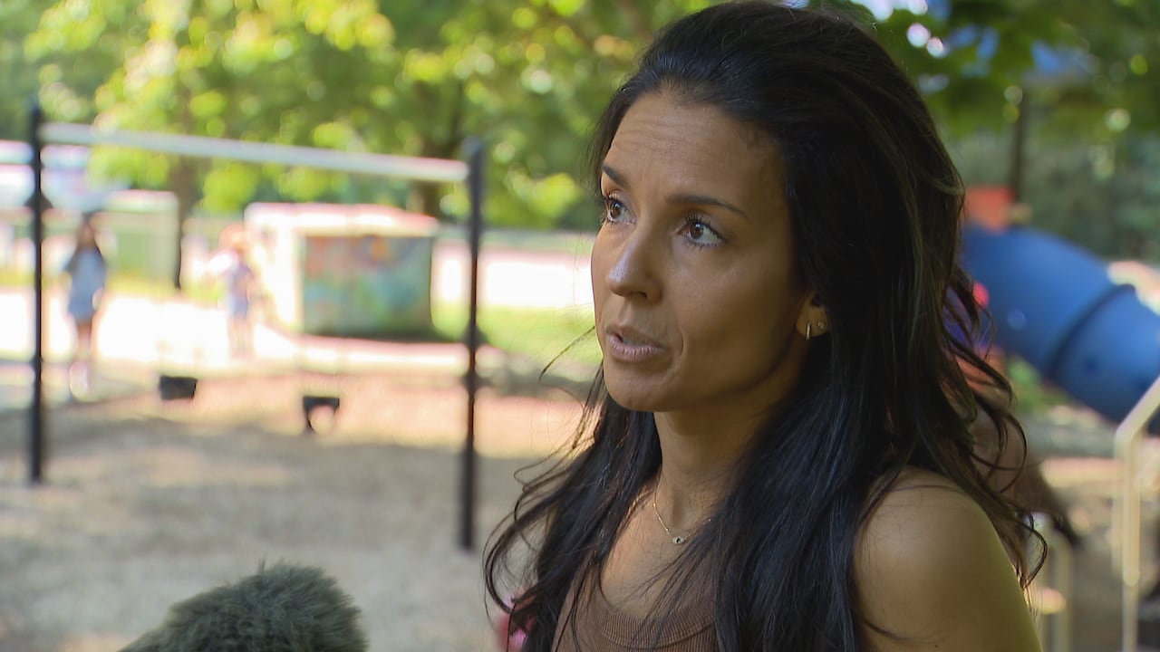 Headshot of a woman with long, dark hair with playground equipment in the background.