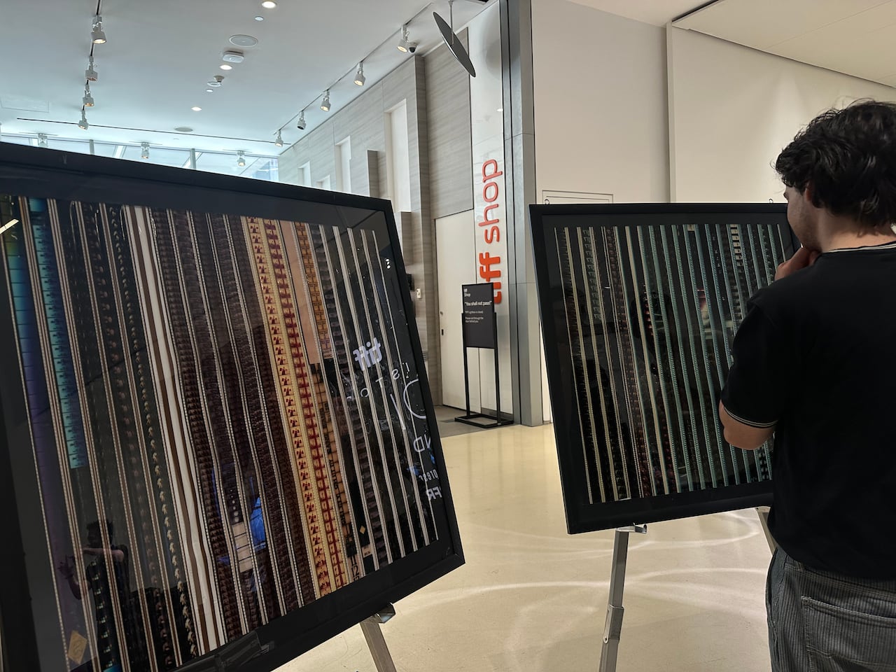 A person wearing black looks at two frames of film strips.