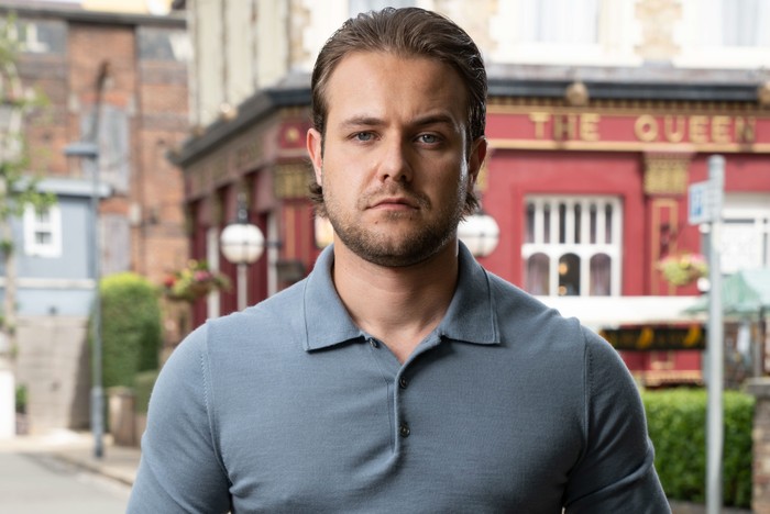 570801,TITLE:Eastenders Matthew James-Bailey as DC Craig Ingram, stood in front of the Queen Victoria, in key art for EastEnders