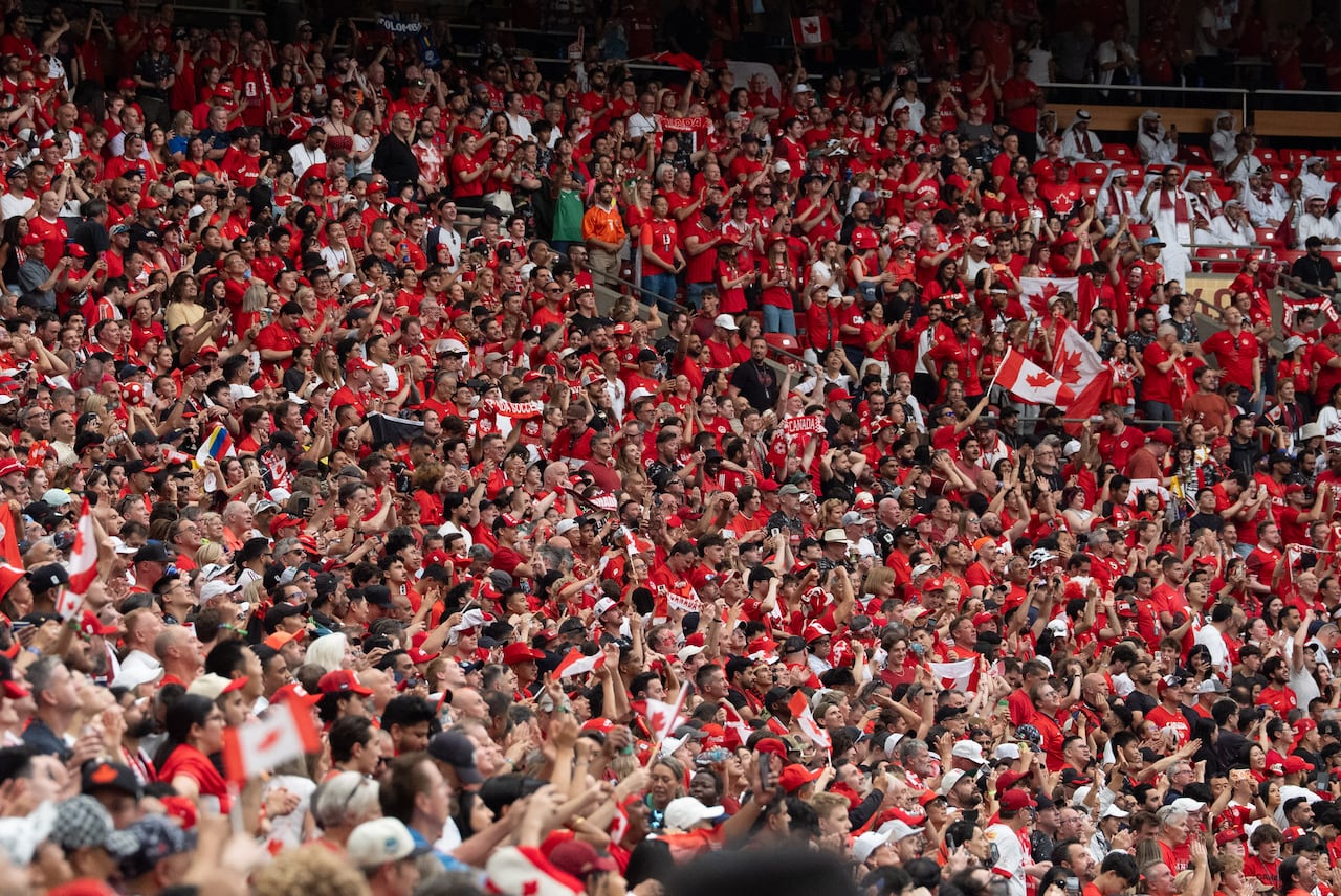 A large crowd of soccer fans wearing red inside a stadium.