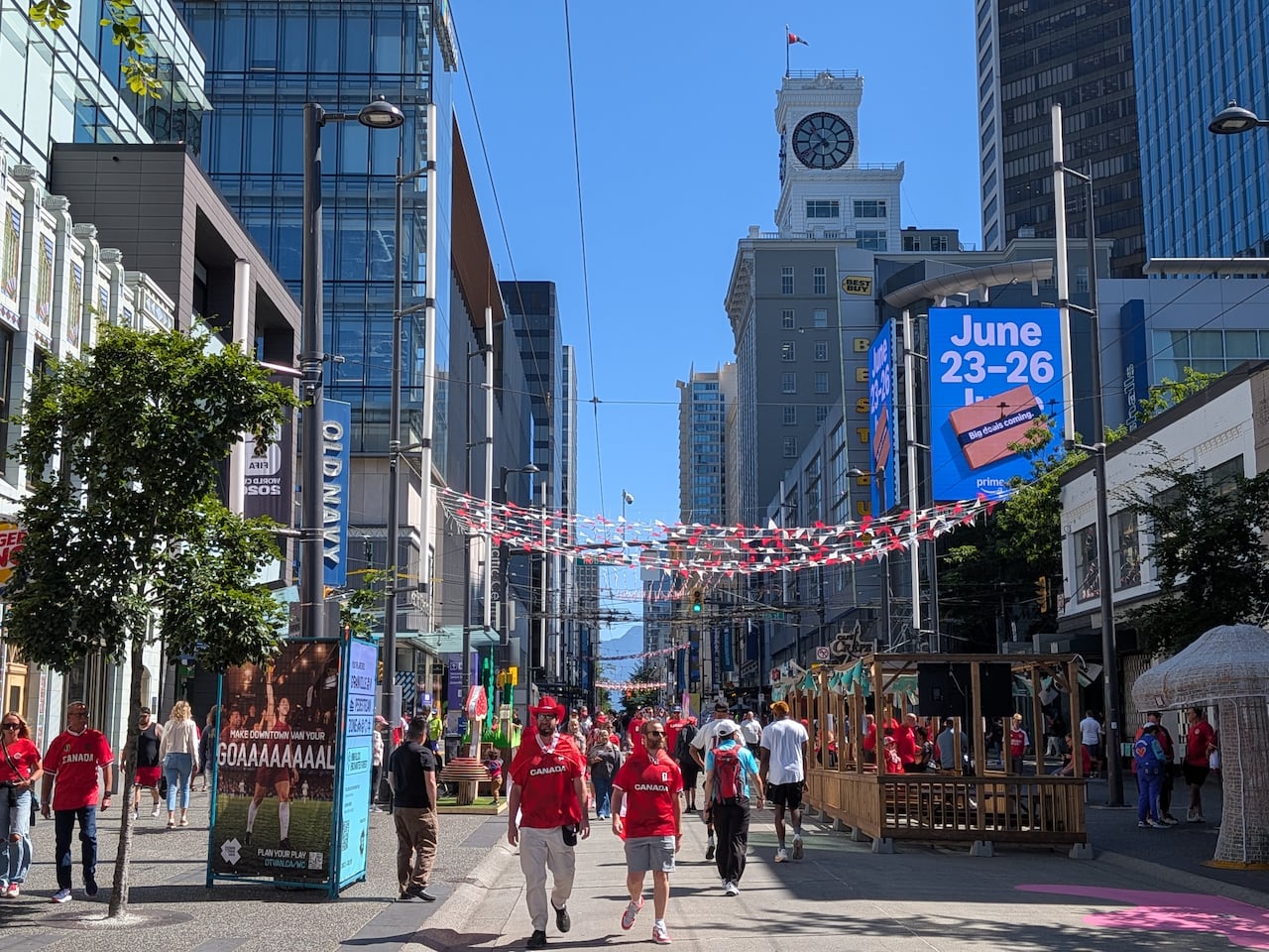 People in red shirts walk down a city street decorated in red and white.