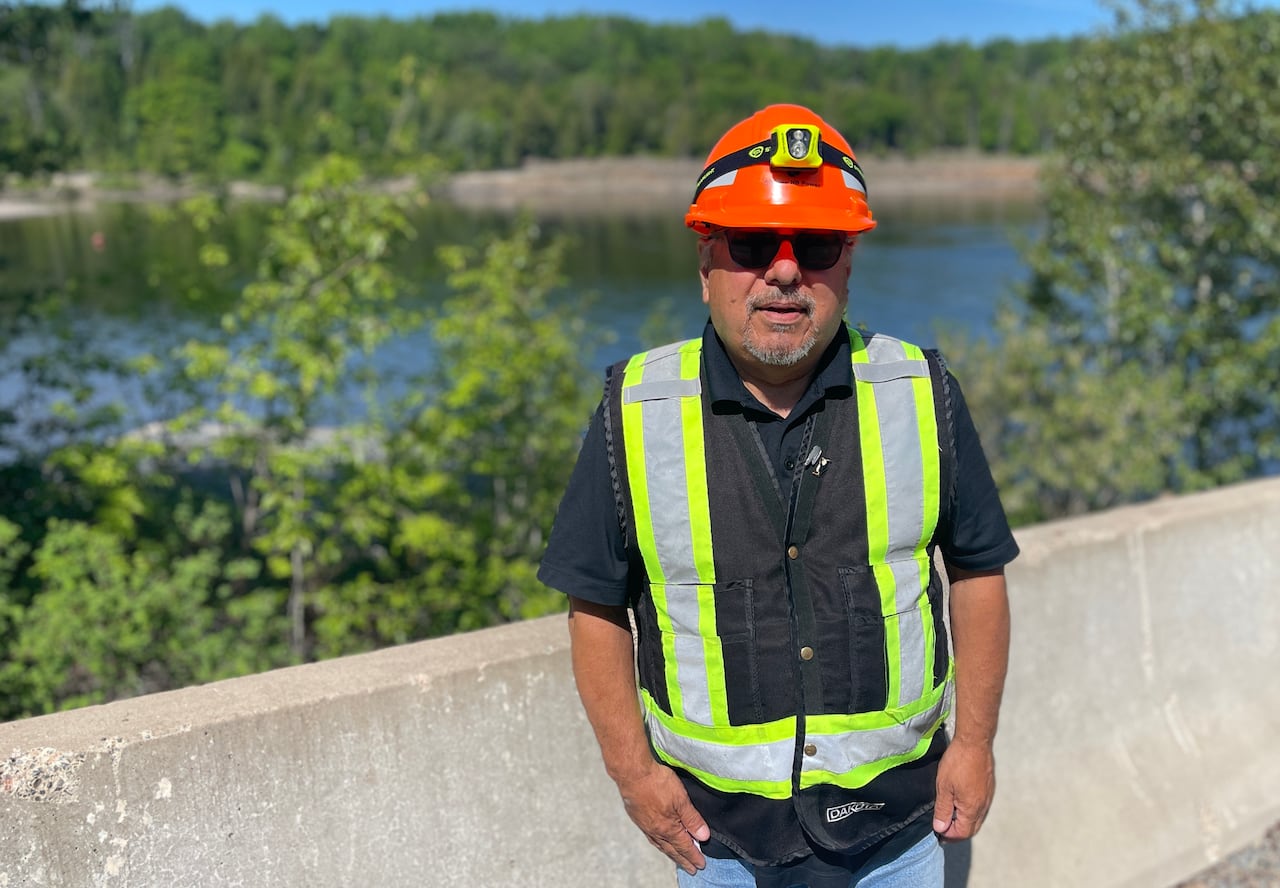 A man in a construction uniform standing in front of water.