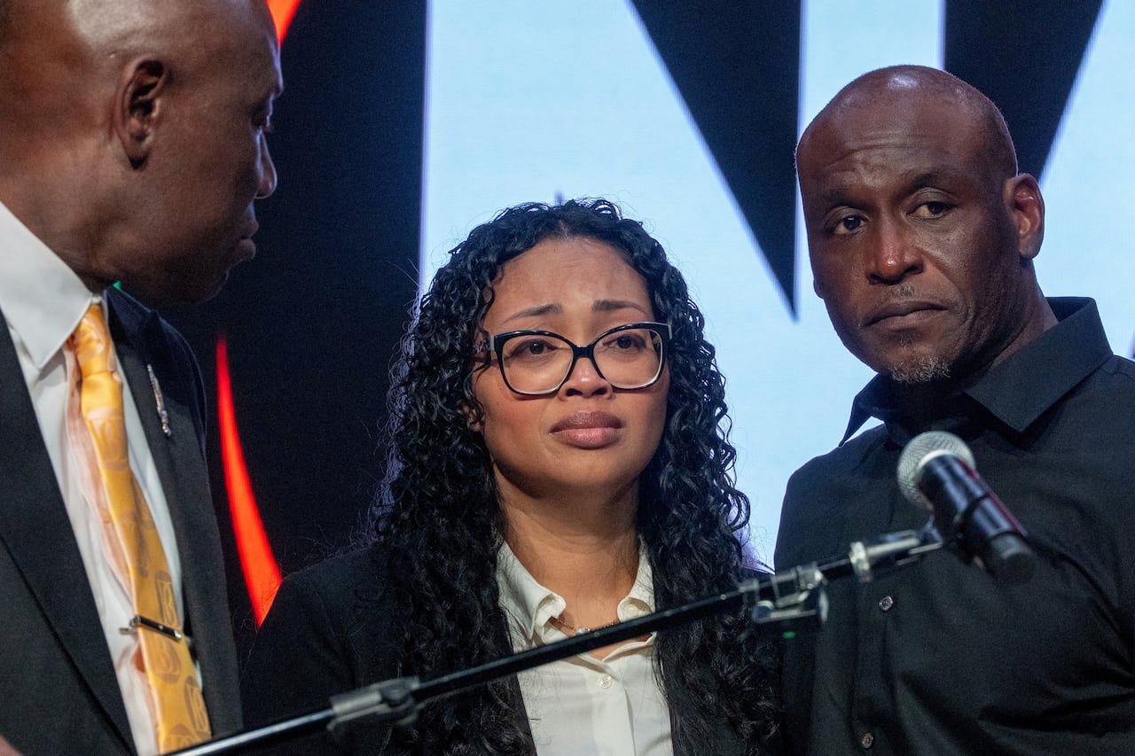 A man and a woman stand in front of a microphone.