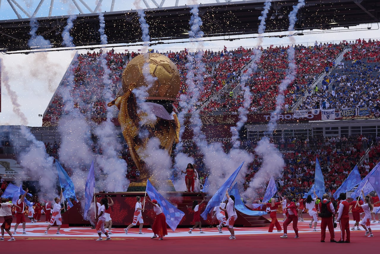 Fireworks erupting as performers dance in a stadium during an opening ceremony.