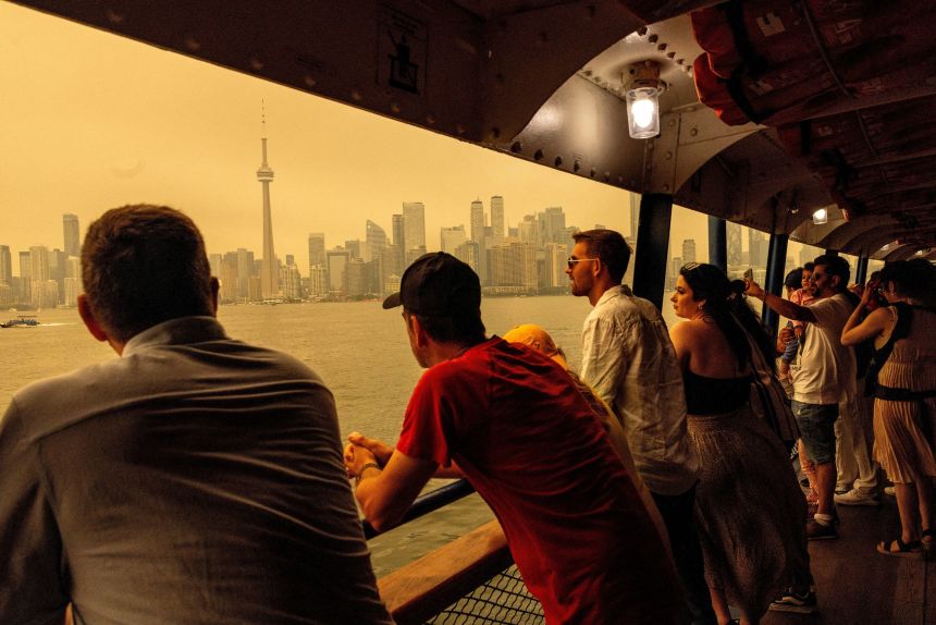 People ride the ferry to Toronto Island, as wildfire smoke from northwestern Ontario, combined with an intense heat wave, fills the sky in Toronto, Ontario, Canada, on July 15.
