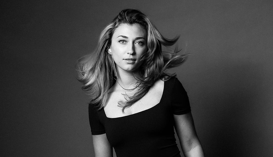 Martina Myskohlid faces the camera wearing a black dress, with her hair in motion.