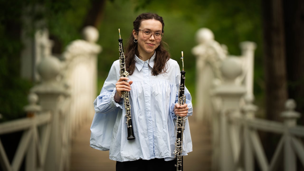 Emma Ahern holds an oboe in one hand and an English horn in the other.