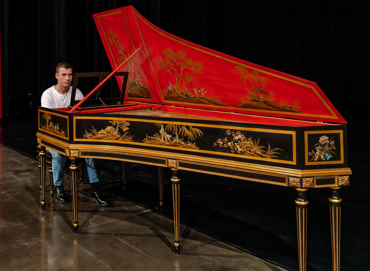 Karl-Frédéric Bolte sets at the keboard of an ornately painted harpsichord.