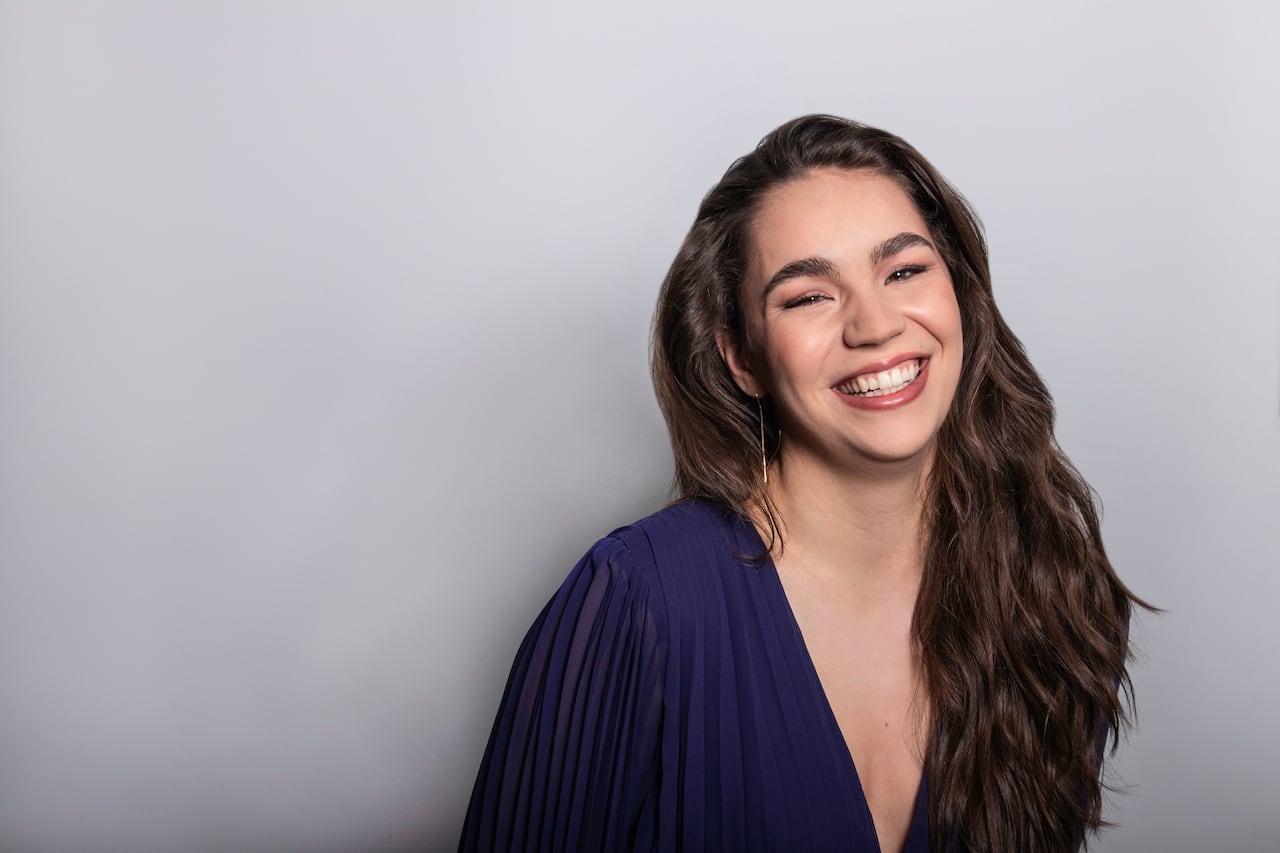 Zoe McCormick has a big smile on her face, wearing a deep blue dress.