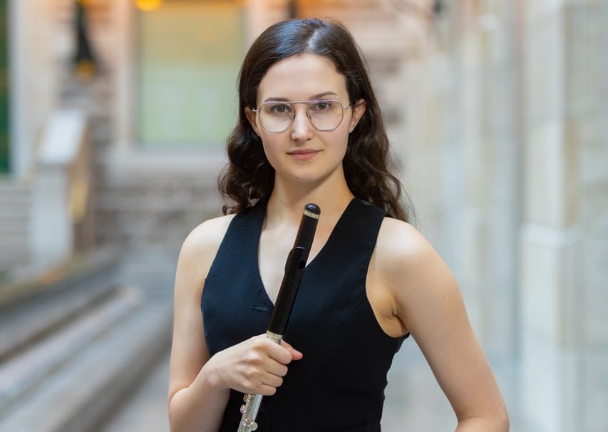 Annie Noël-de-Tilly wears a sleeveless black vest and faces the camera holding her flute.