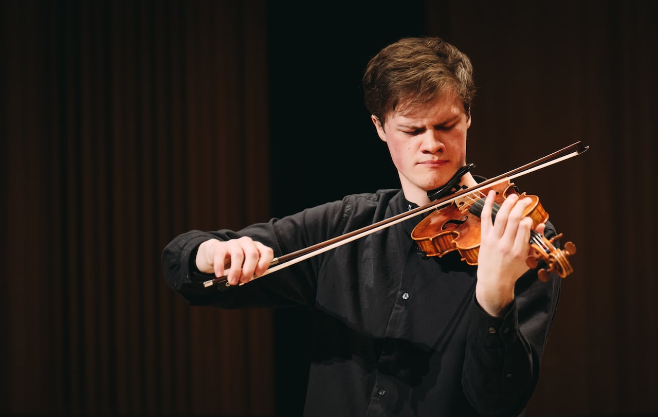 Joey Machin has a look of intense concentration on his face as he plays his violin onstage.