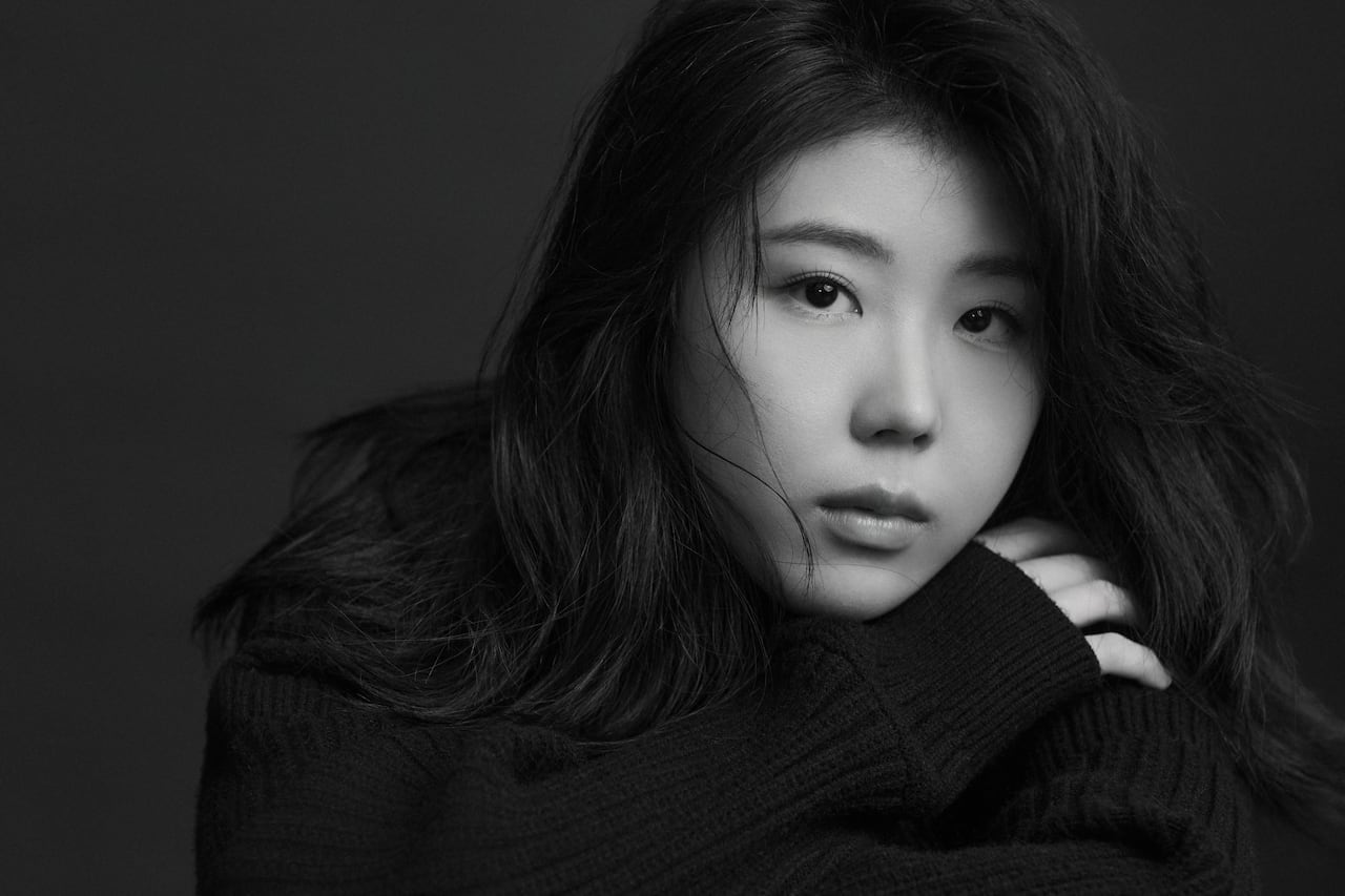 Pianist Sirui Li, wearing black, with her hair flowing partly across her face, looks straight into the camera.