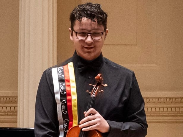 Dressed in black, Daniel Milliea poses with his viola onstage at Weill Recital Hall i New York City.