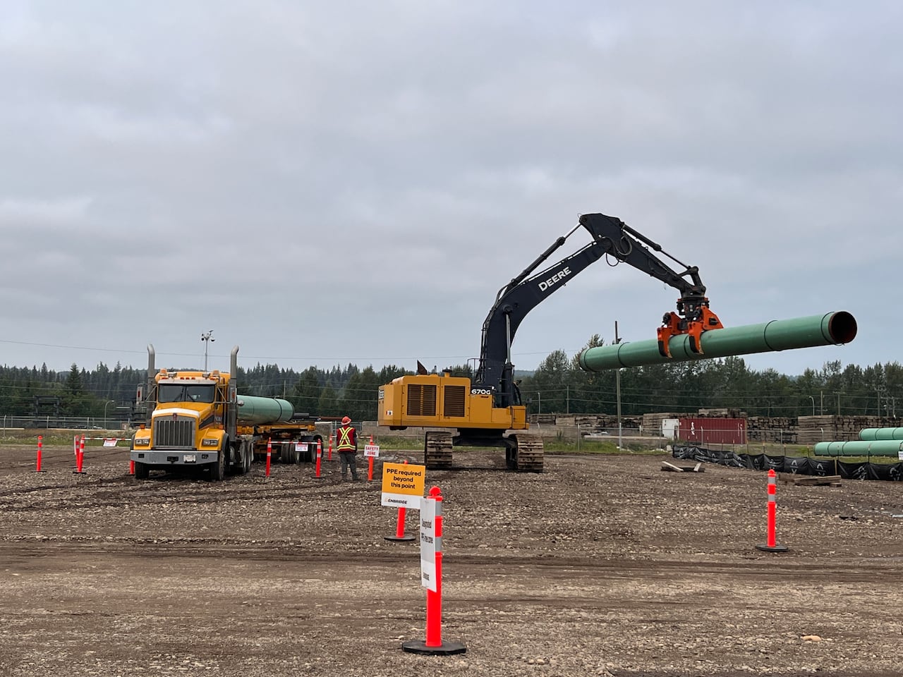 A machine lifts a section of pipe in an industrial site.