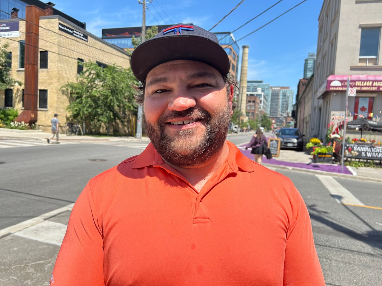 A man with a black hat and orange shirt
