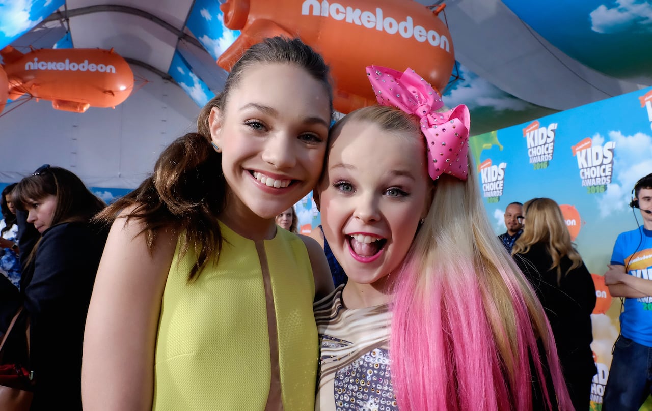 two girls smile for a photo wearing yellow and pink outfits.