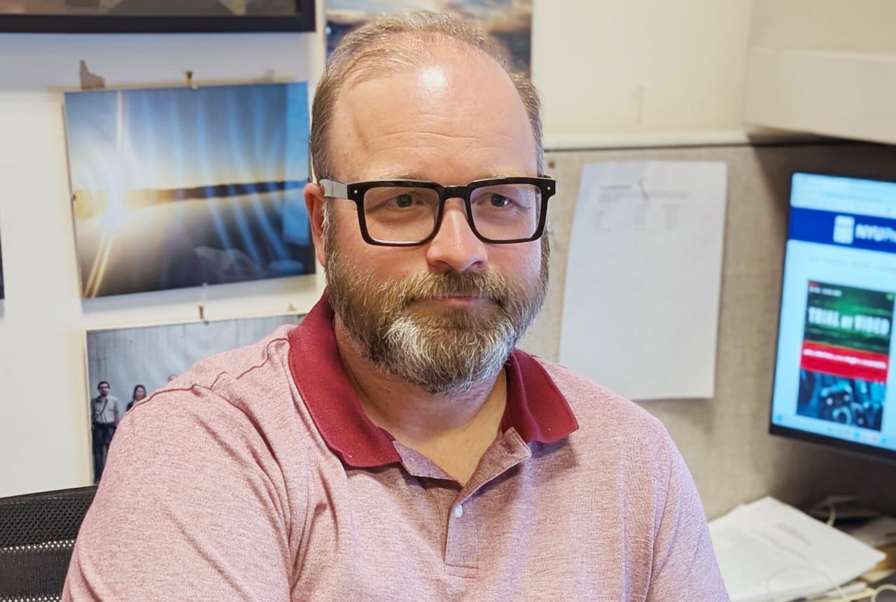 A man in glasses in front of a computer.