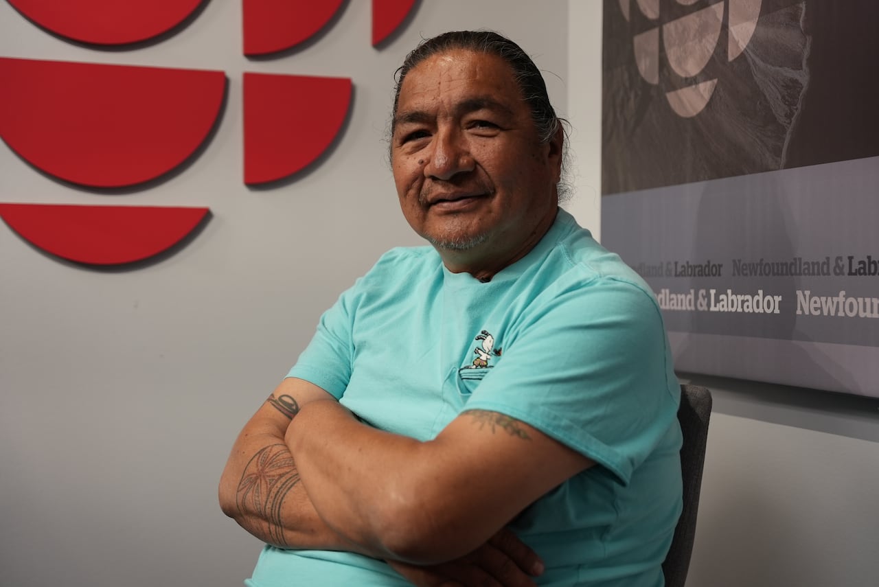 An Innu man wearing a turquoise t-shirt poses for a photo in a CBC studio.