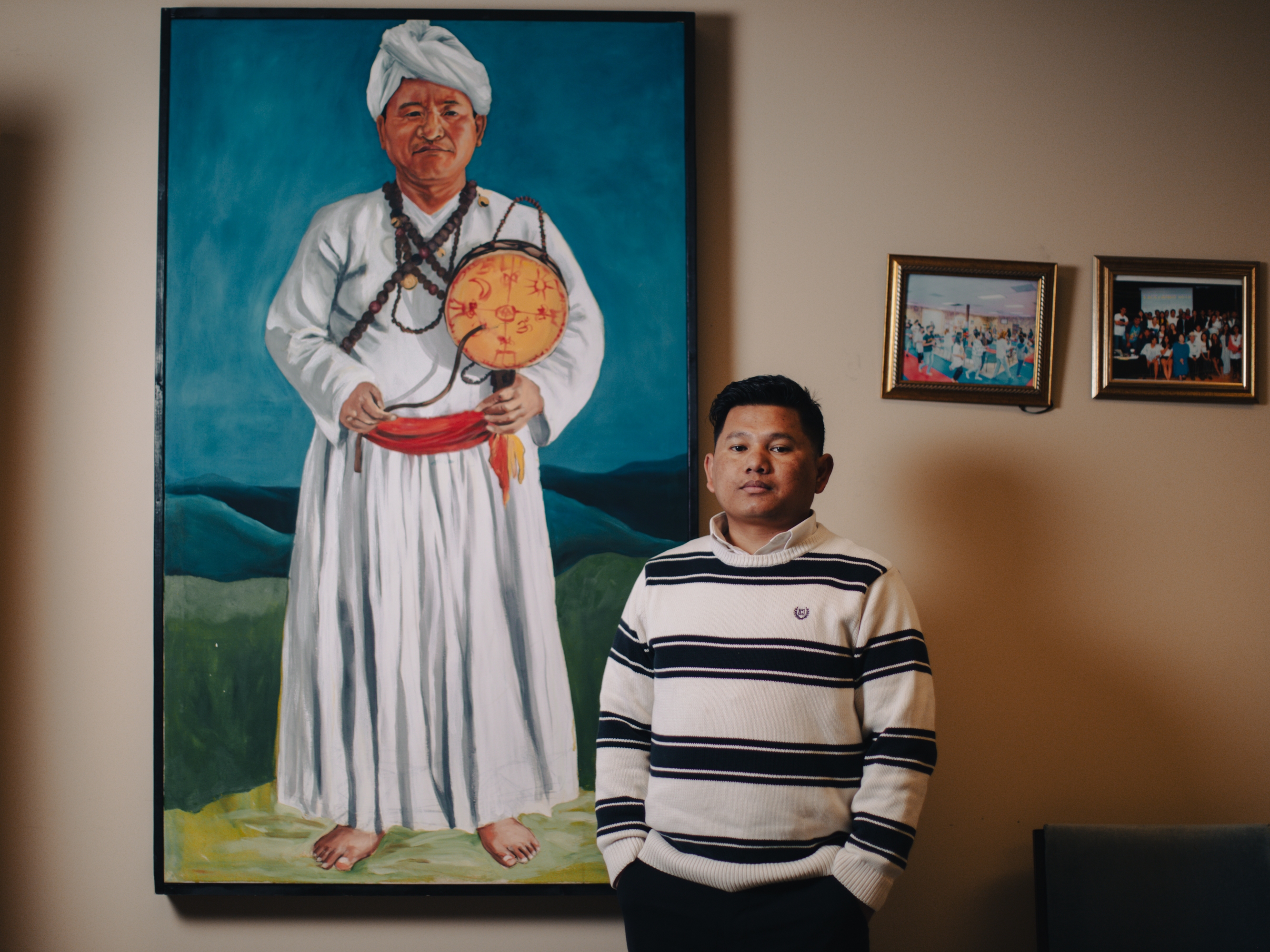 Robin Gurung, co-founder of Asian Refugees United, poses for a portrait next to a depiction of a Nepali-speaking Bhutanese shaman in Harrisburg, Pa., on April 17, 2025. Gurung says there have been shamans in his family, including his father.