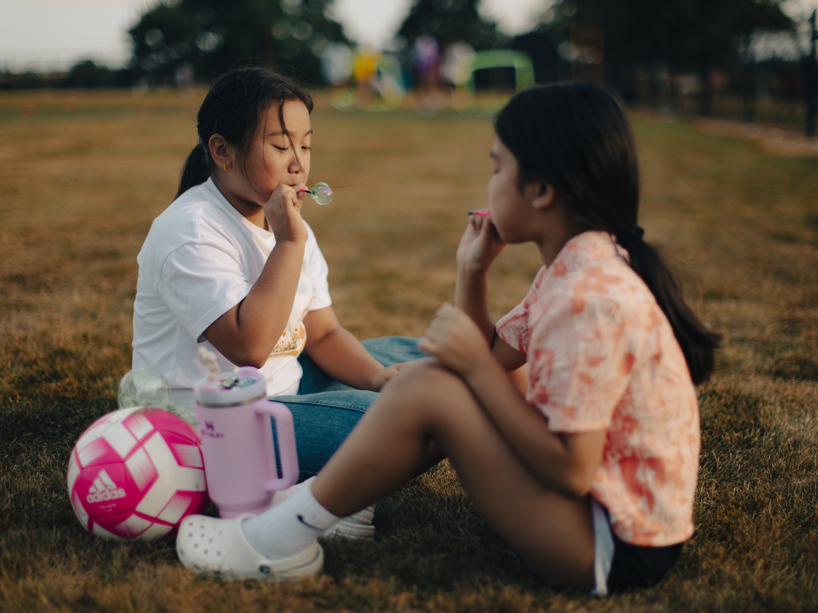 Cousins Kavya Saru, 9, and Denisha Saru, 8, blow bubbles as their sisters play soccer in Harrisburg, Pa., on Sept. 15, 2025.
