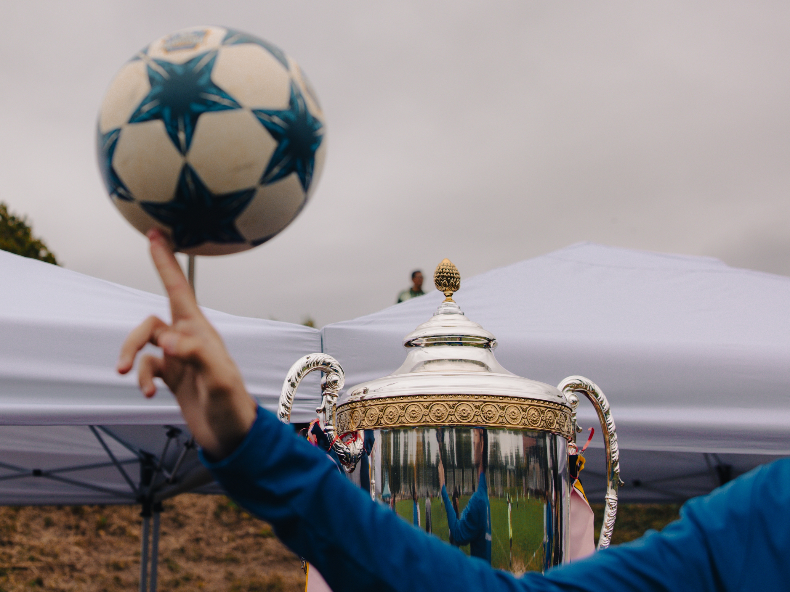 Shabin Subba, the head coach for ARU's Soccer for Success program, idly spins a soccer ball while watching the Kalu Singh Tamang Memorial Championship in Harrisburg, Pa., on Sept. 21, 2025.
