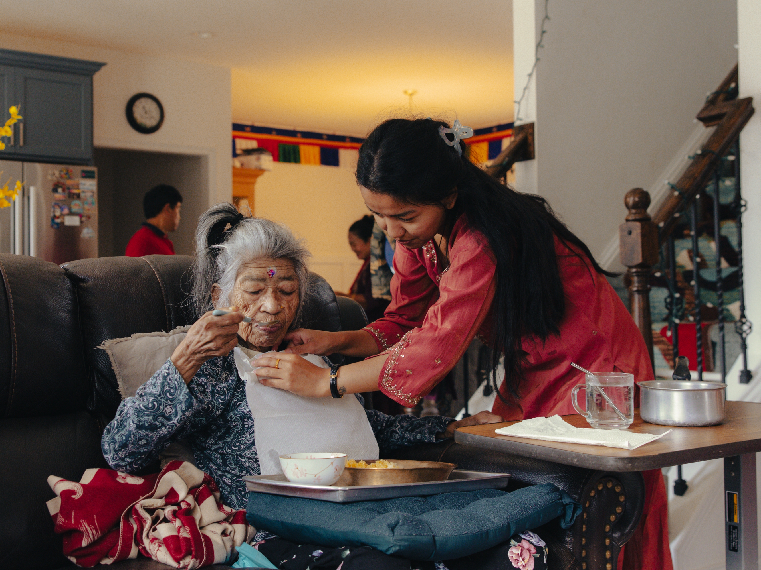 Manju Gurung helps feed her grandmother, Phul Gurung, at their home amid holiday festivities in honor of Tihar, the Hindu festival of lights and animals, in Mount Holly Springs, Pa., on Oct. 23, 2025.