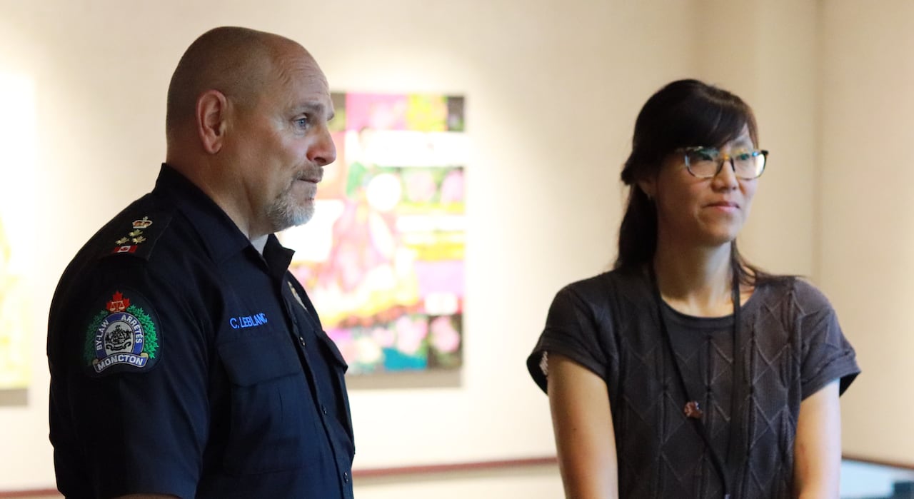 Two people in dark clothing standing looking off-camera.