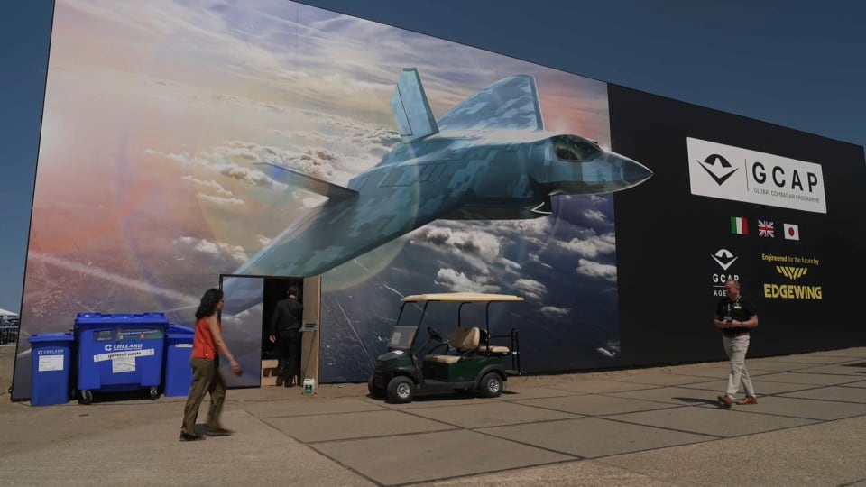 Two people walk past a billboard depicting a fighter jet.