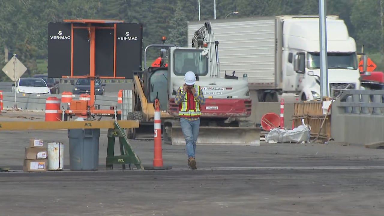 A construction worker speaks on the phone on a roadway construction site.