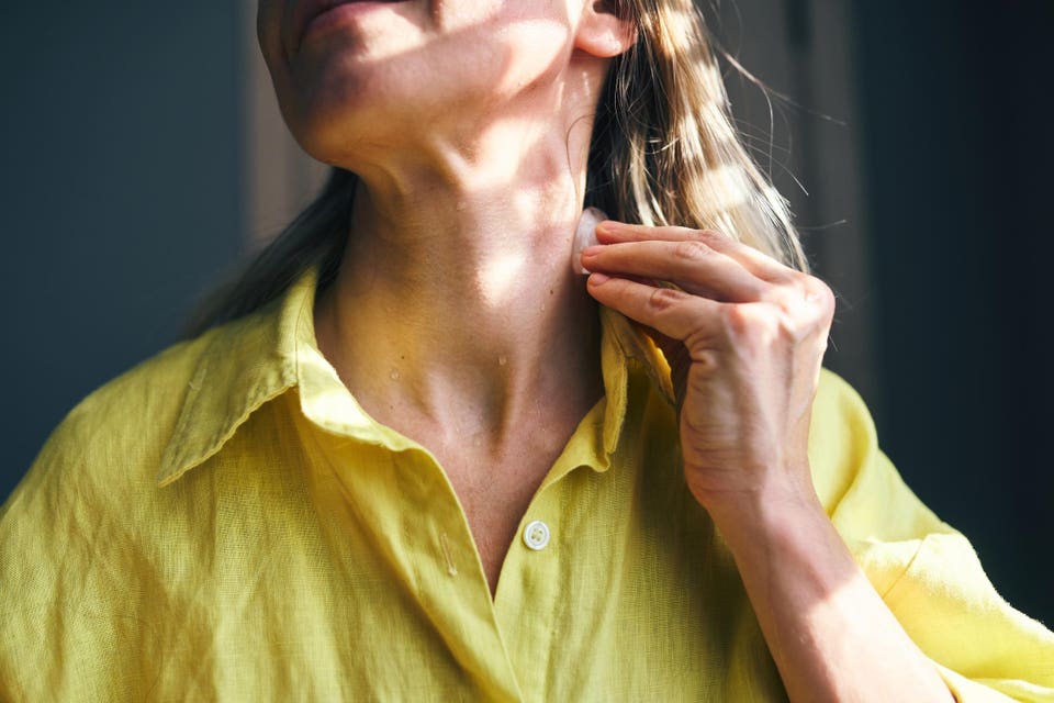 Woman cooling down sweating neck with ice in summer heat