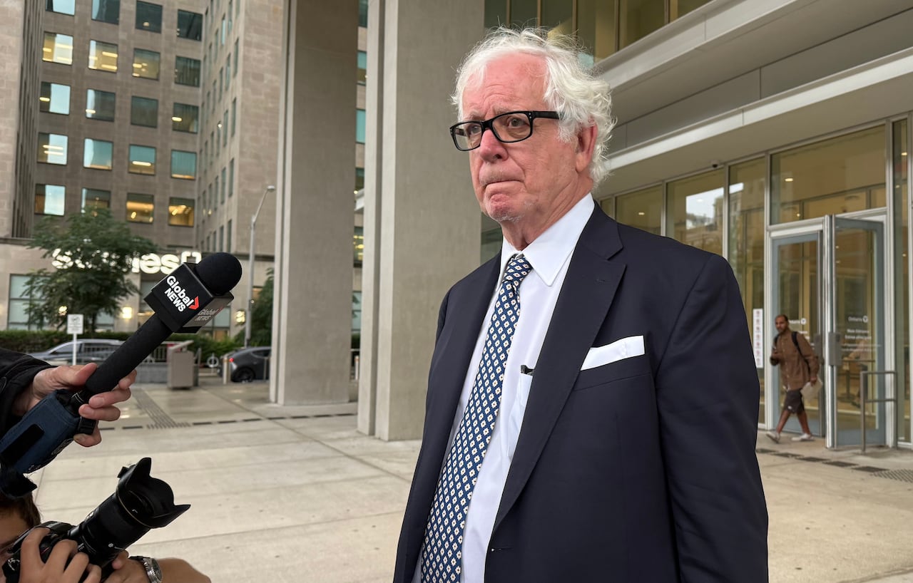 Man in a suit standing outside a courthouse.