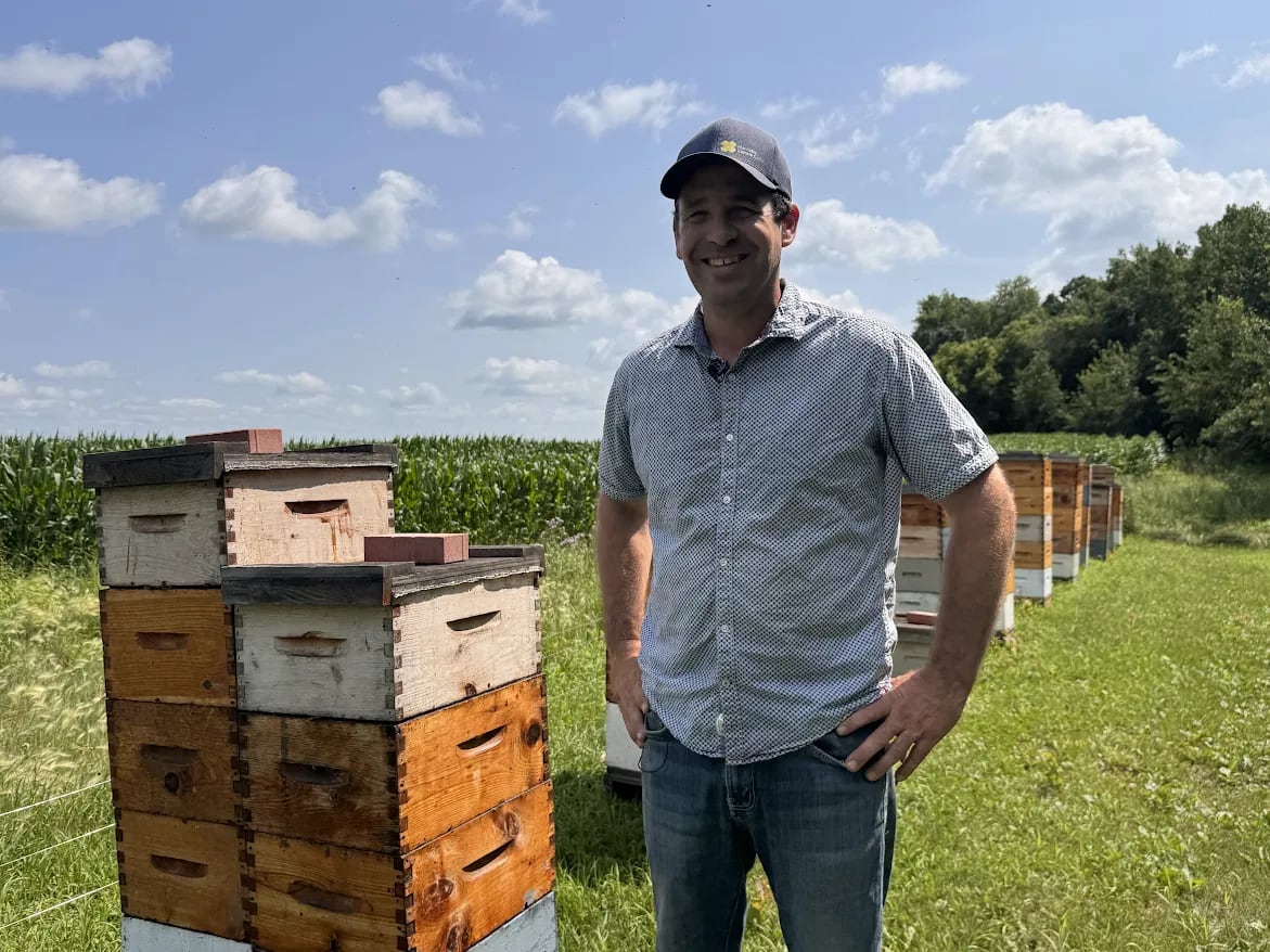 The beekeeper on his farm beside some of his bee colonies.
