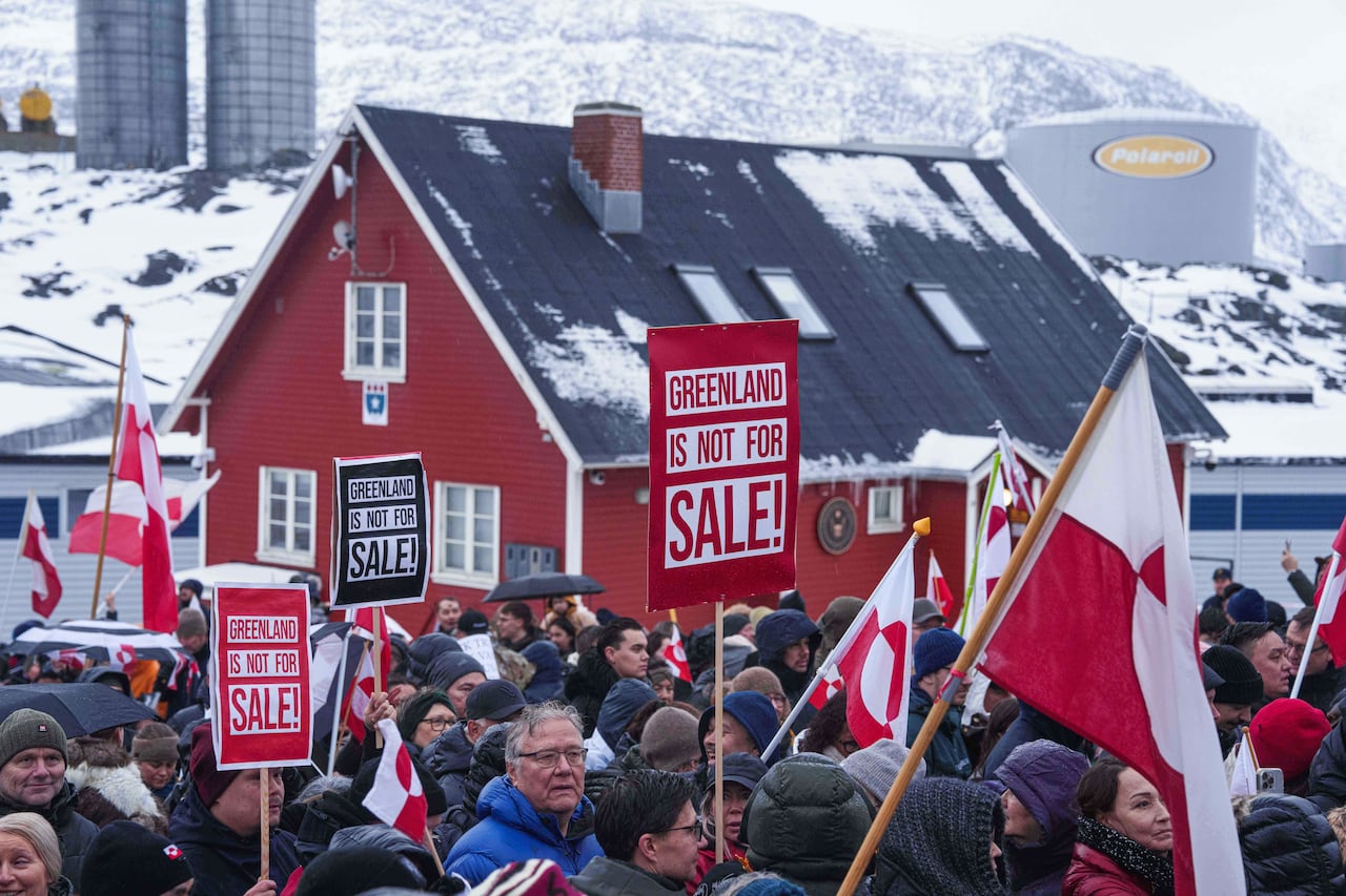 A crowd carrying signs that say Greenland is not for sale