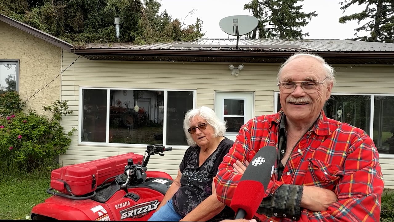 A couple outside a house speaking to a mic.