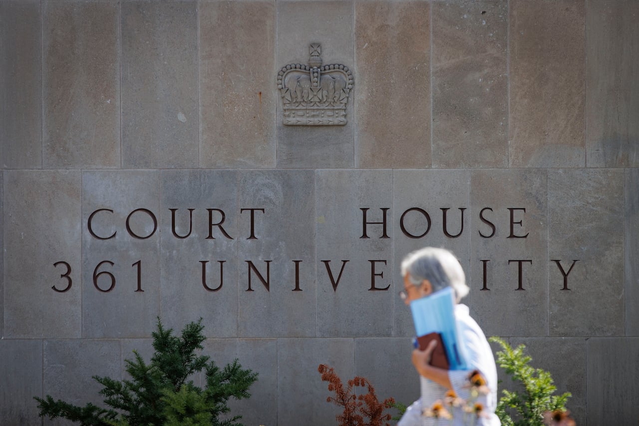 A person is seen walking by a stone wall marked "Court House 361 University."